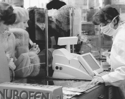 A pharmacy worker in Russia wears a respiratory mask while serving customers to protect herself from a flu epidemic in 1999. (Reproduced by permission of AP/Wide World Photos)